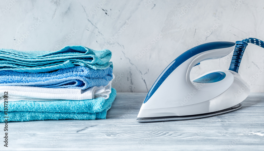 housekeeping set with towels and iron on laundry background