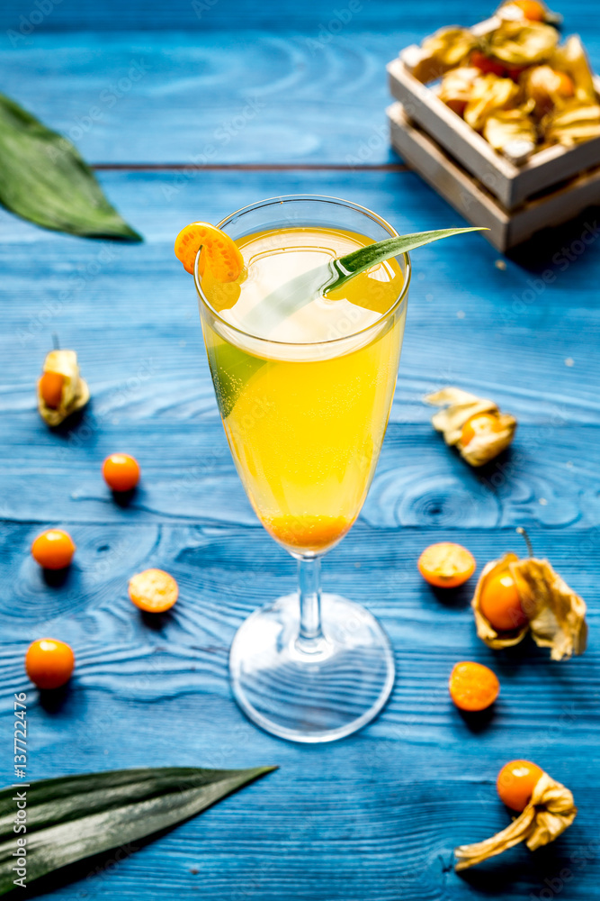 cocktail with physalis in glass on wooden background