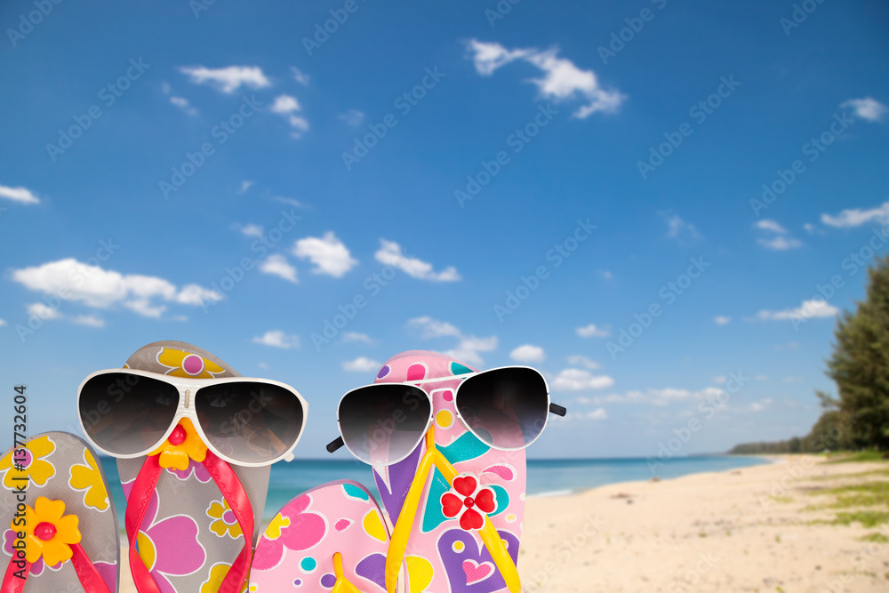 beach shoes with sunglasses on tropical sea and sky background.