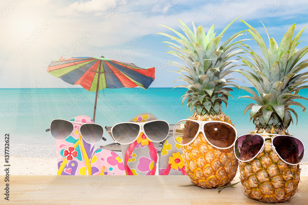 Pineapple and shoes with sunglasses on wood floor,blue sky and tropical beach background,concept hel