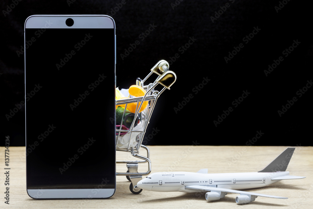 mobile phone with airplane model and shopping cart on wood ,Online shopping and tour concept