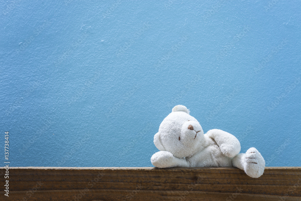 teddy bear on old wood ,blue wall background.