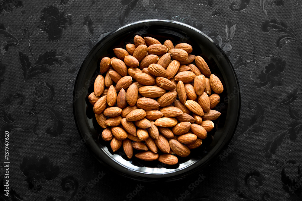 Close up almonds nut in black plate on dark background