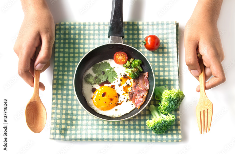 Breakfast with fried egg and bacon in dark pan on the table