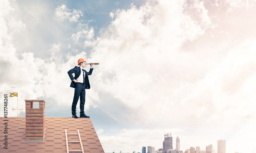 Engineer man standing on roof and looking in spyglass. Mixed med