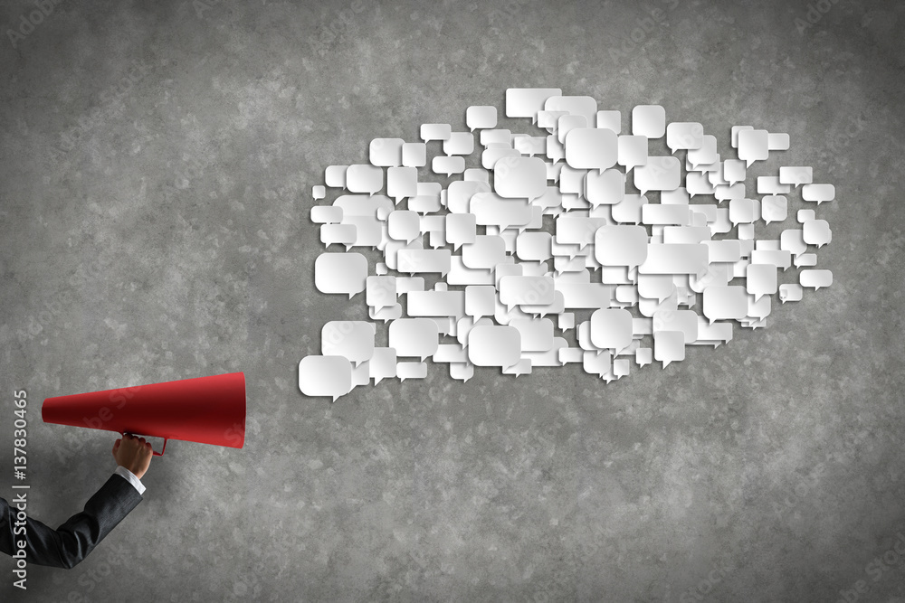 Hand of businesswoman holding red paper trumpet and speech cloud coming out