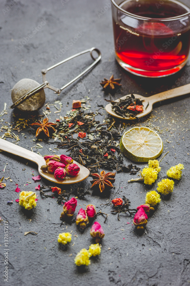 Teacup and herbs on dark stone background