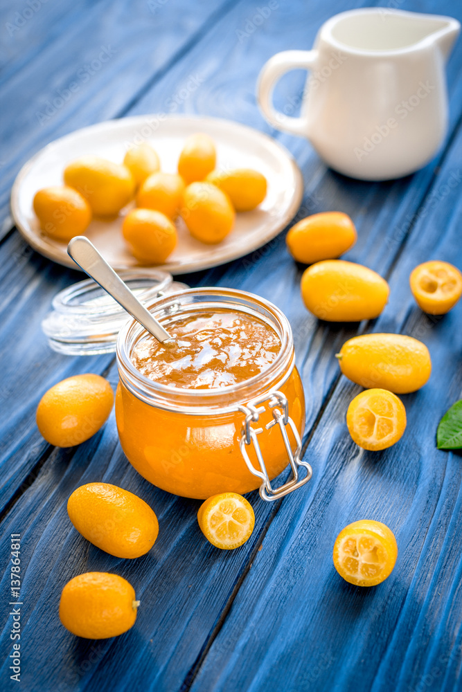 kumquat on plate and jam in jar at wooden table