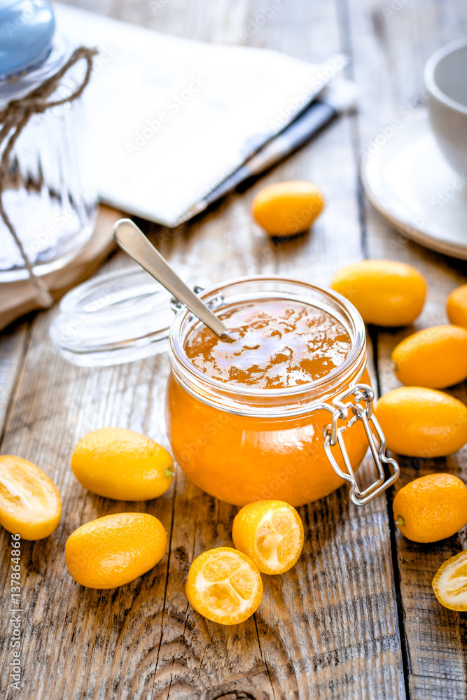 kumquat on plate and jam in jar at wooden table