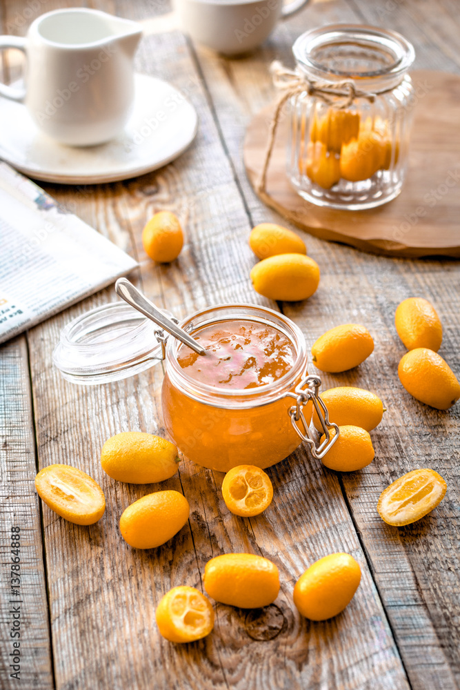 kumquat on plate and jam in jar at wooden table