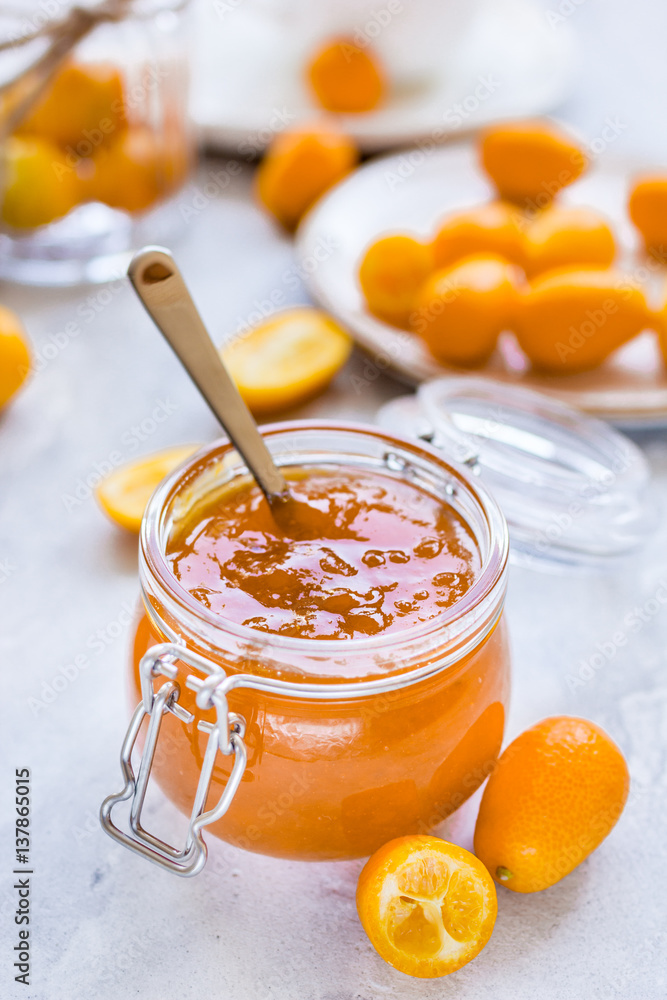 kumquat on plate and jam in jar at gray background