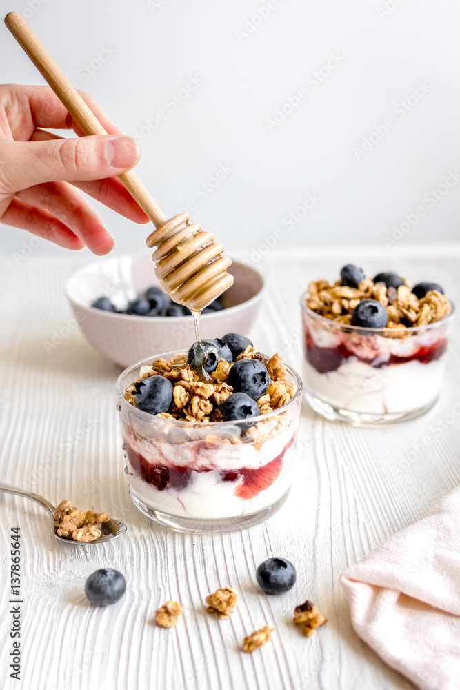 Cooking breakfast with granola and berries on white kitchen background