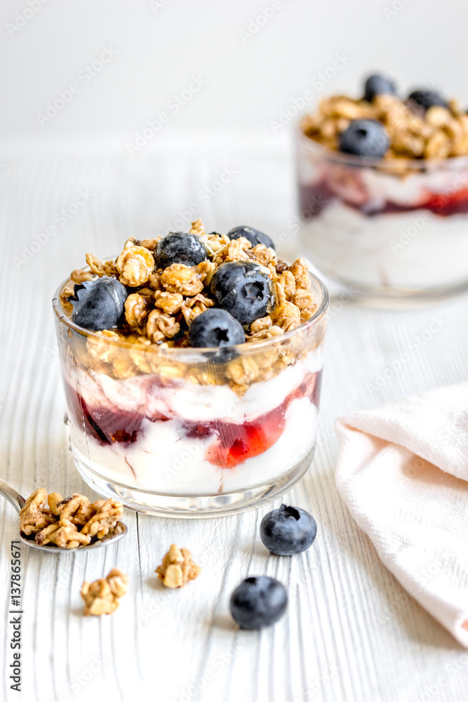 Morning granola with yogurt and berries on white kitchen background