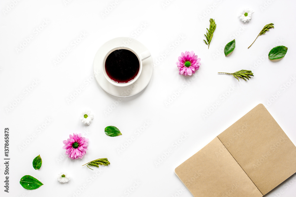 Petals, cup and copybook on table background top view mock up