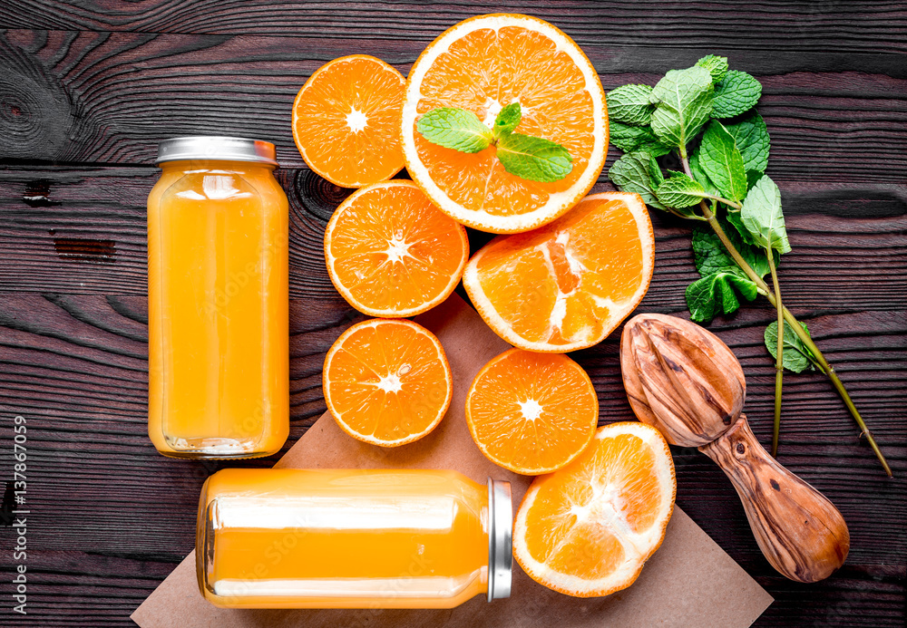 Homemade juice bottles with orange and mint on table top view