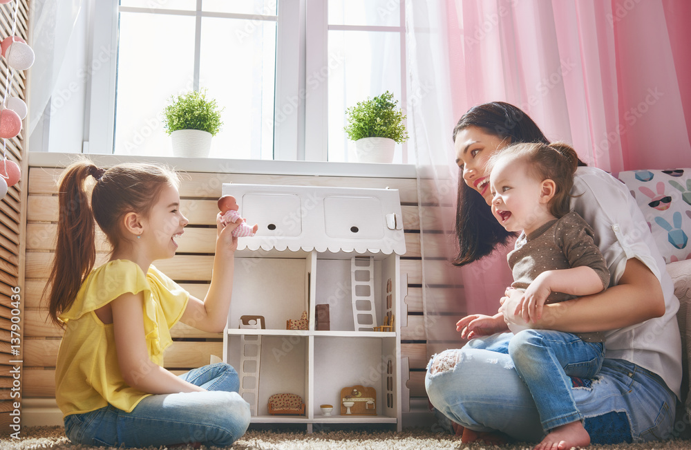 mother and daughters play with doll house