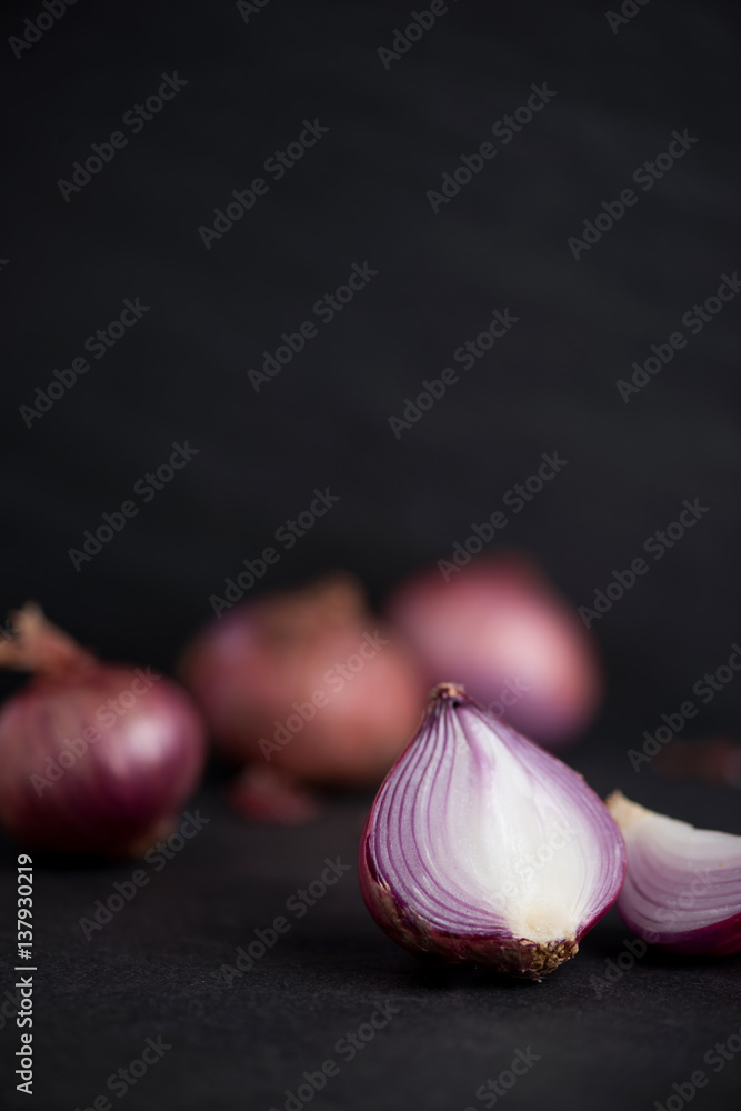 Full and half cut spanish onions on dark background.