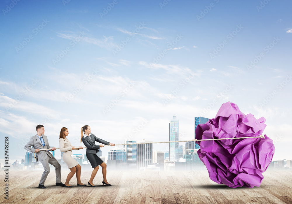 Young business people outdoors and huge paper ball as symbol of creativity