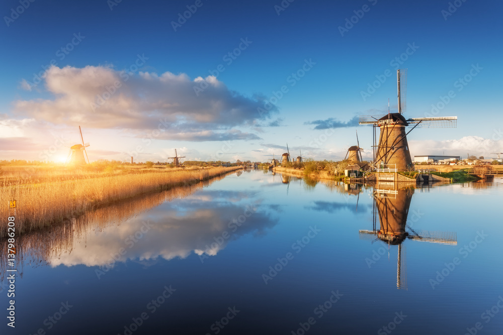 Windmills at sunrise. Rustic landscape with amazing dutch windmills near the water canals with blue 