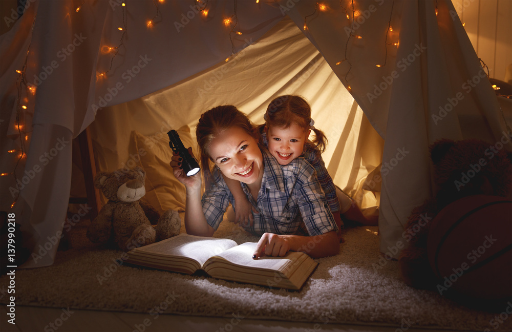 mother and child daughter with a book and a flashlight before going to bed