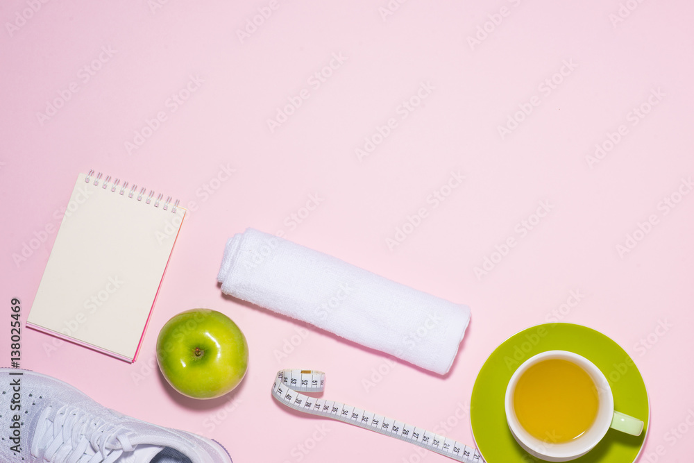 Healthy concept. Sneakers, tea, apple and measure tape on pastel color background.