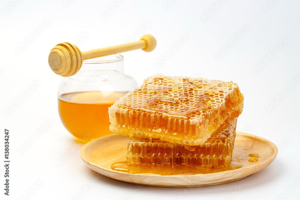 Honeycomb with jar and honey dipper isolated on white background