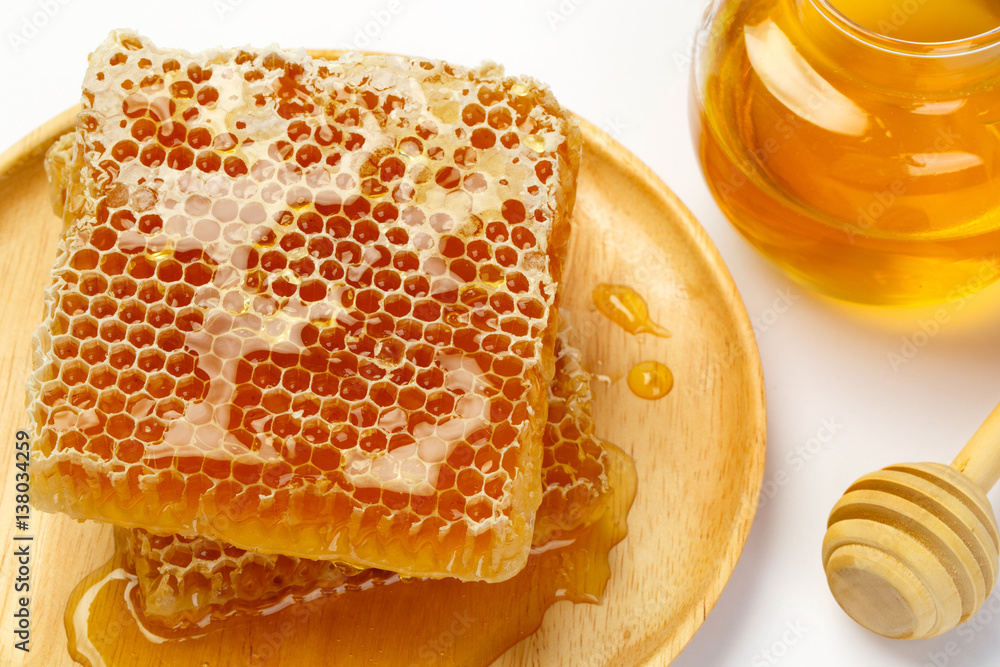 Honeycomb with jar and honey dipper isolated on white background