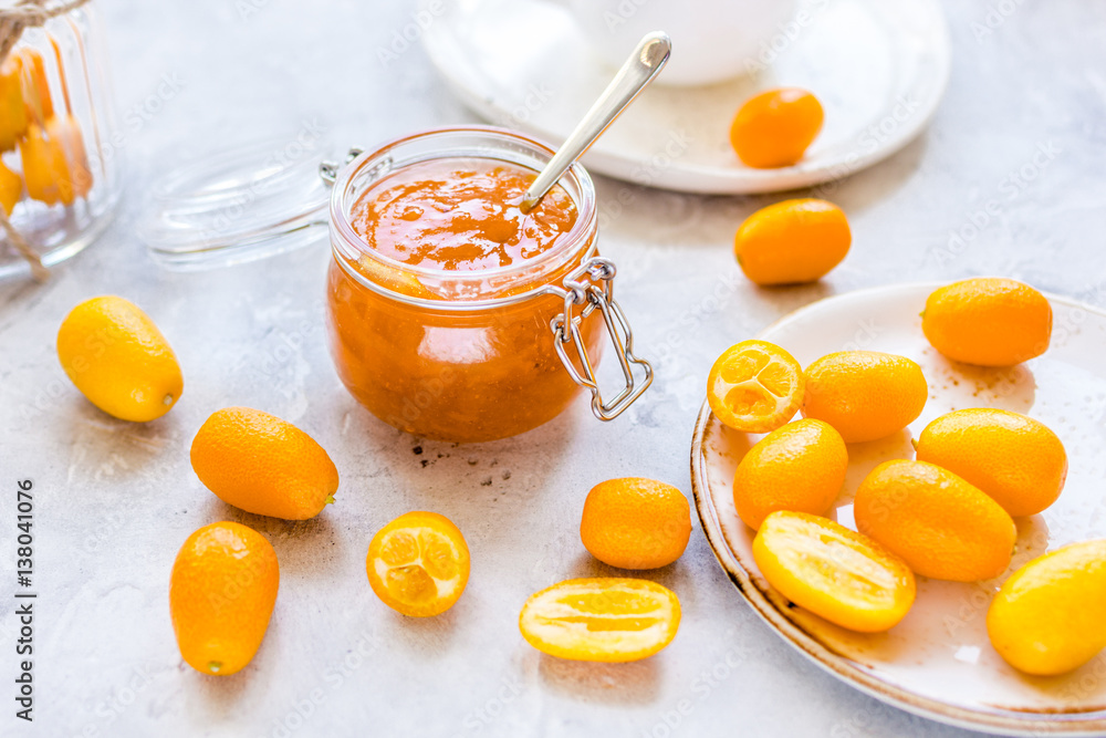 kumquat on plate and jam in jar at gray background