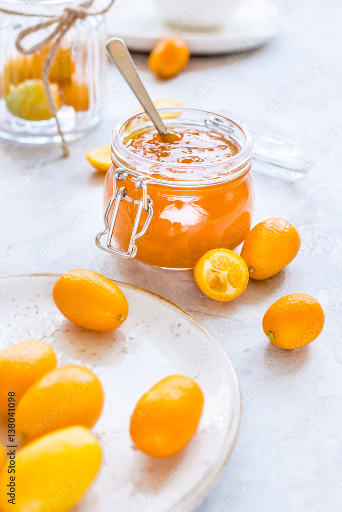 kumquat on plate and jam in jar at gray background