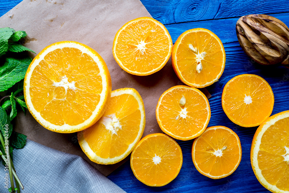 orange juice with mint squeezing on blue kitchen background top view