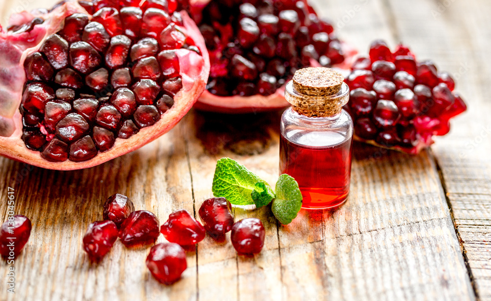 sliced pomegranate and extract in glass on wooden background