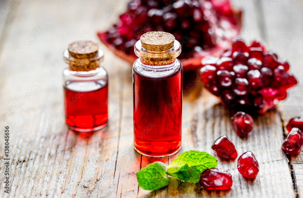 sliced pomegranate and extract in glass on wooden background