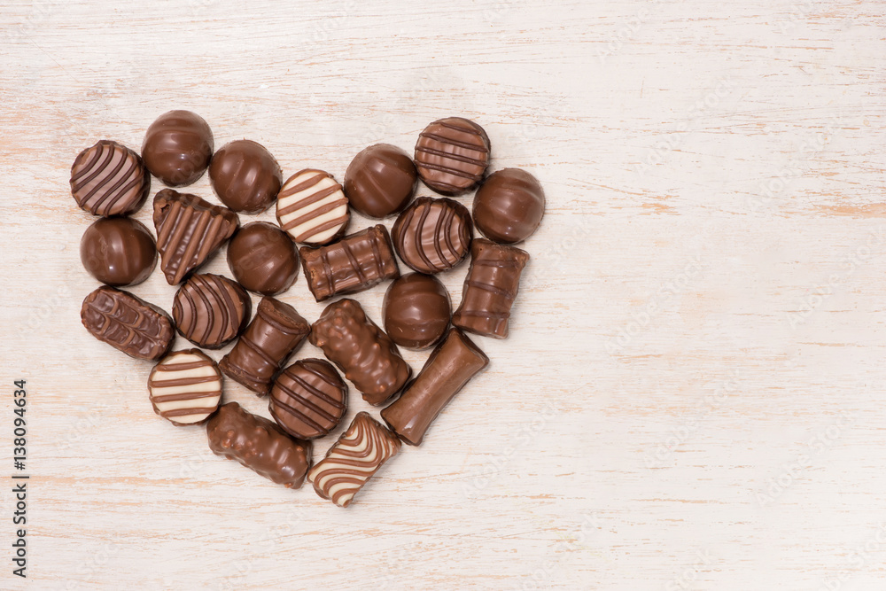 Heart made from chocolate truffles on wooden background.