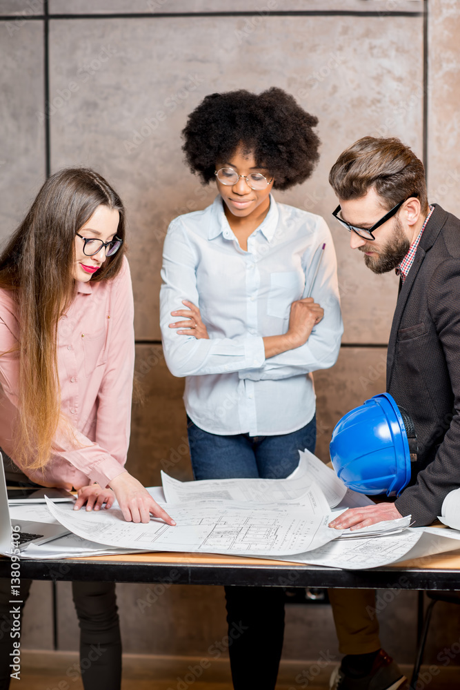 Multi ethnic group of architects or designers working together on the architectural plans at the off