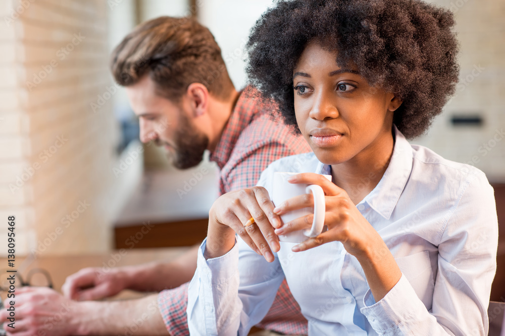 Beautiful african businesswoman and caucasian man working together with laptops and coffee cups near