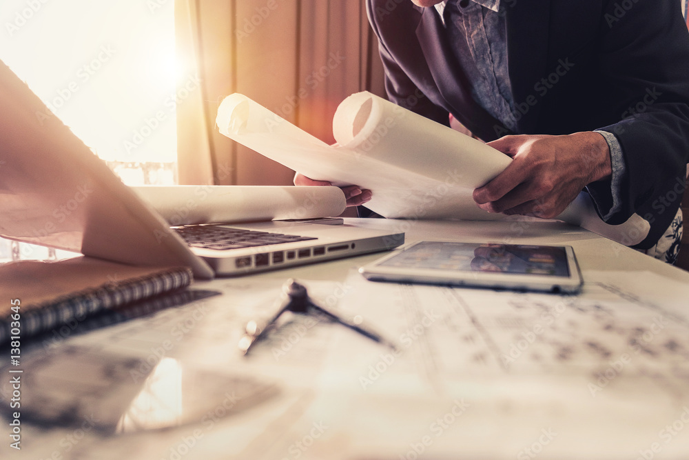 business man hand working and laptop with on on architectural project at construction site at office