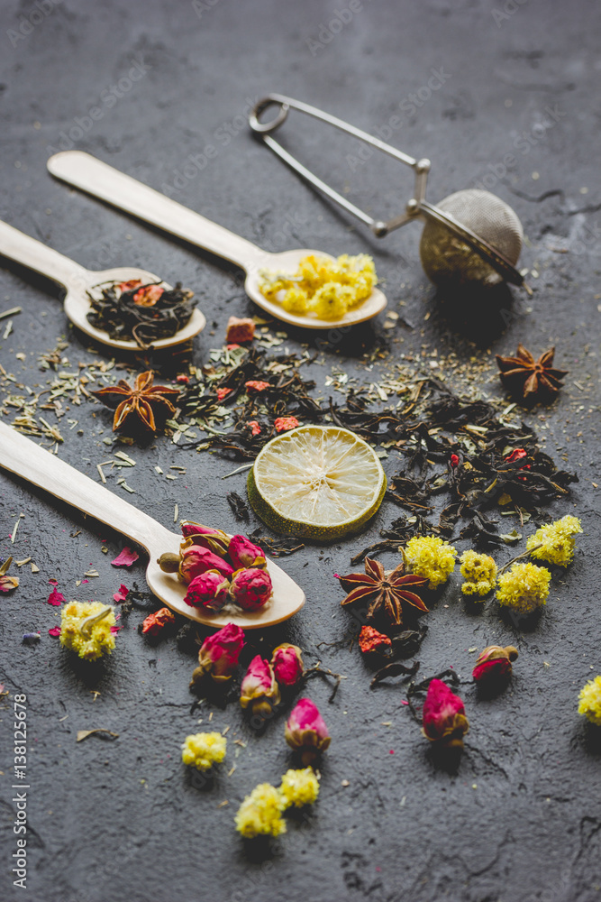 Spoons with herbs on dark stone background