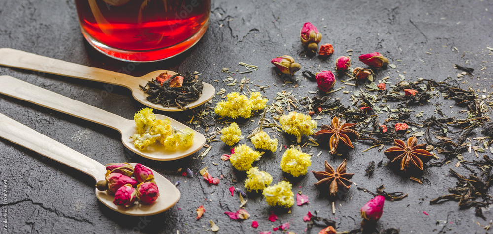 Teacup and herbs on dark stone background