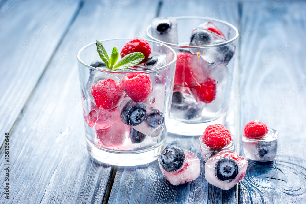 Frozen berries in glass for cocktail on wooden table background