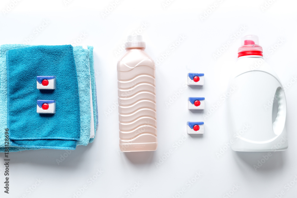 Pile of towels with detergent on white background top view