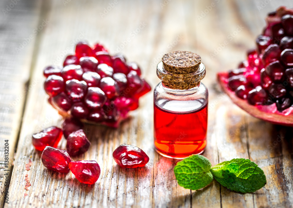 sliced pomegranate and extract in glass on wooden background