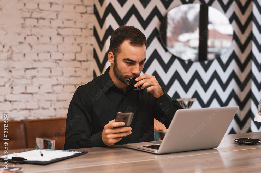 Handsome young businessman working on project and drinking coffee