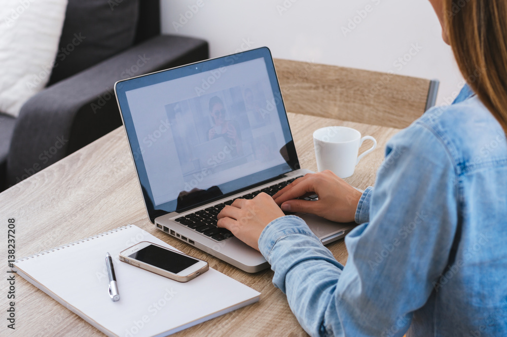 Rear view of a carefree student working on laptop while sitting