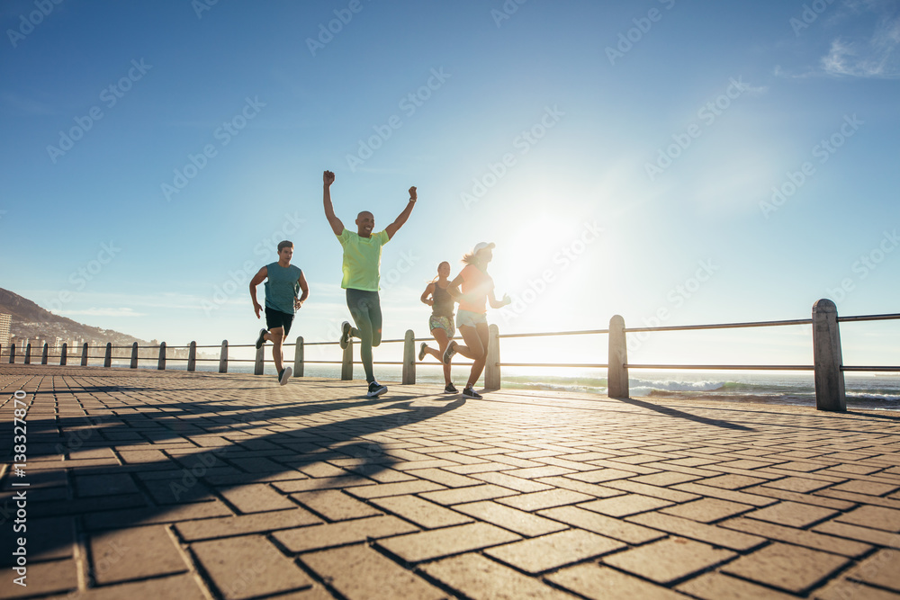 Group of young people running along seaside