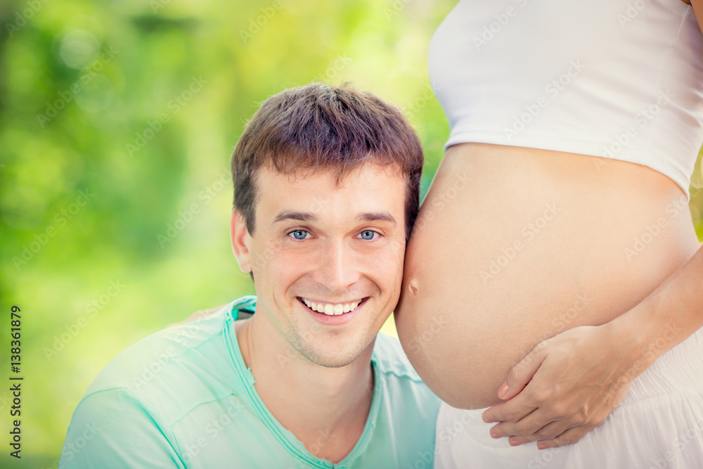 Happy man holding belly of pregnant woman