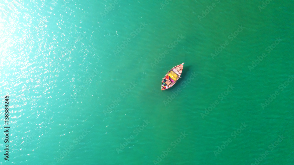 Fishing boat floating in the sea. The beautiful bright blue water in a clear day.Aerial view.Top vie