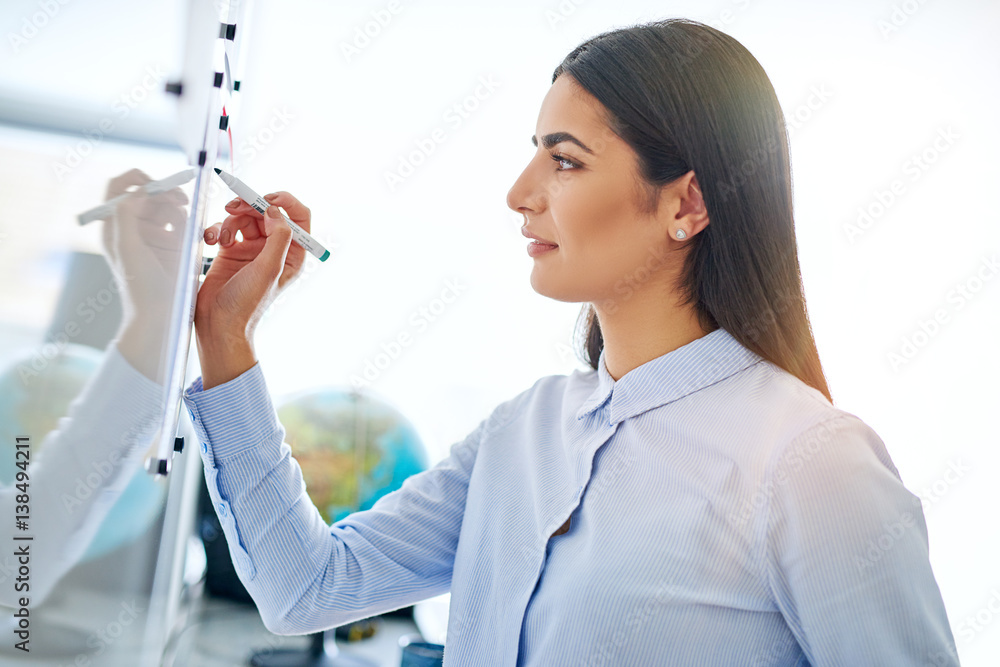 Young woman writing on board with marker