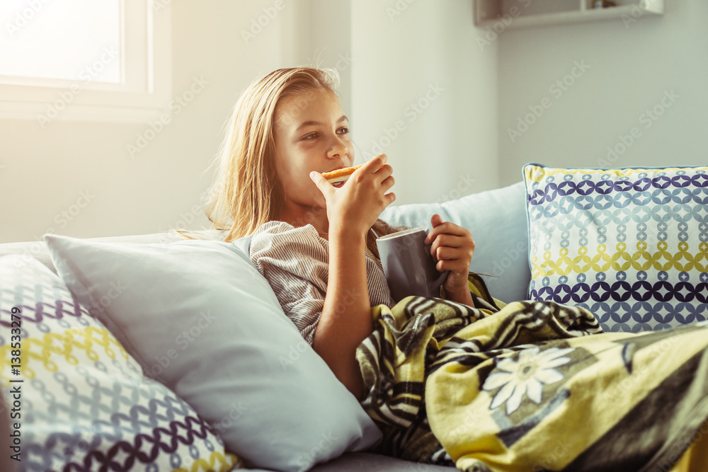 Girl in blanket relaxing on couch in living room