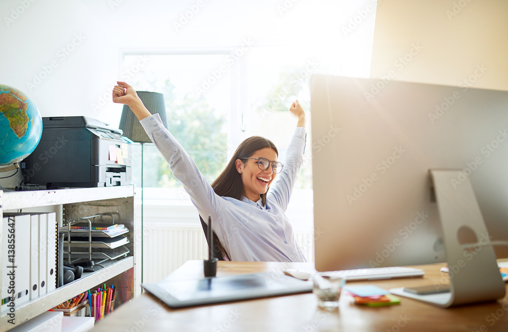 Woman celebrating something while seated at desk