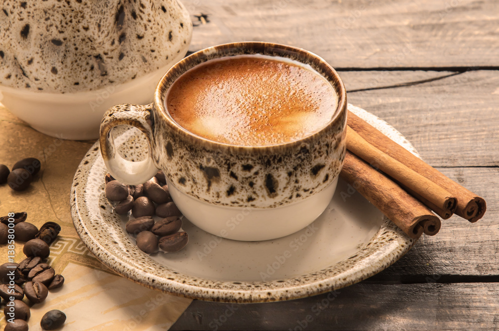 Coffee Cup and beans with cinnamon sticks on Wooden Table.